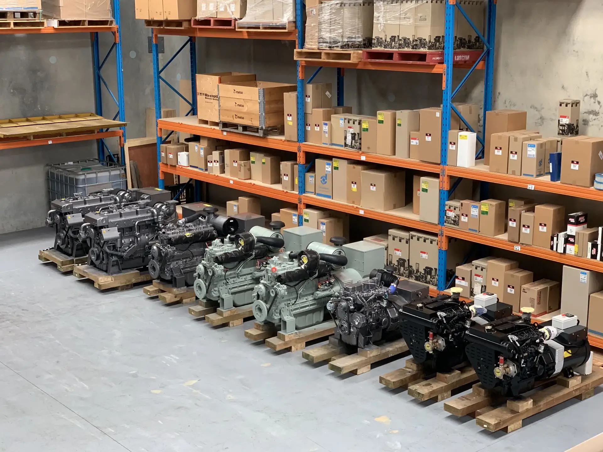 A row of marine engines and gensets on pallets in OPS's Wangara warehouse, stacked in front of parts shelving