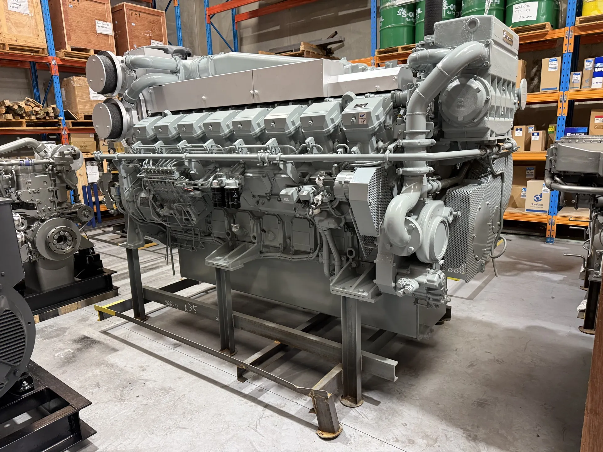 An S16R2 marine engine on a fabrication stand in OPS's Wangara warehouse, surrounded by parts stock and other engines