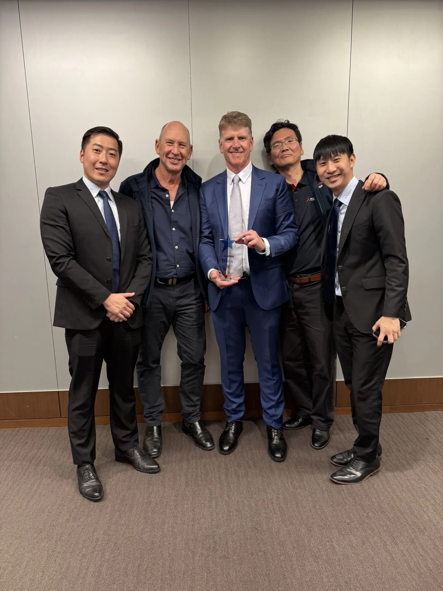 Five members of the OPS team holding a glass award marking ten years as Mitsubishi Heavy Industries's exclusive Australian marine engine dealer