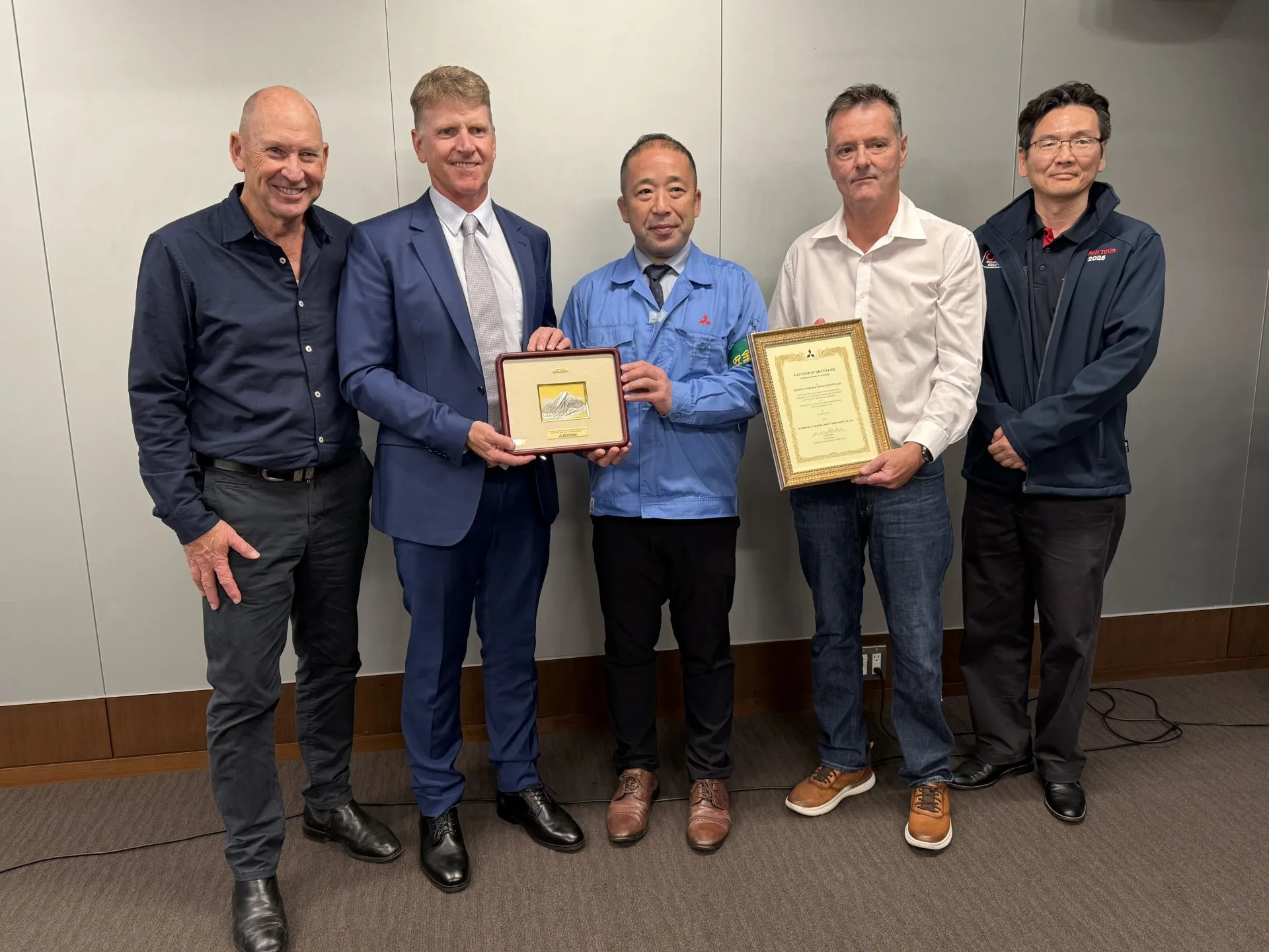 OPS and Mitsubishi Heavy Industries representatives exchanging a framed award and a letter of recognition